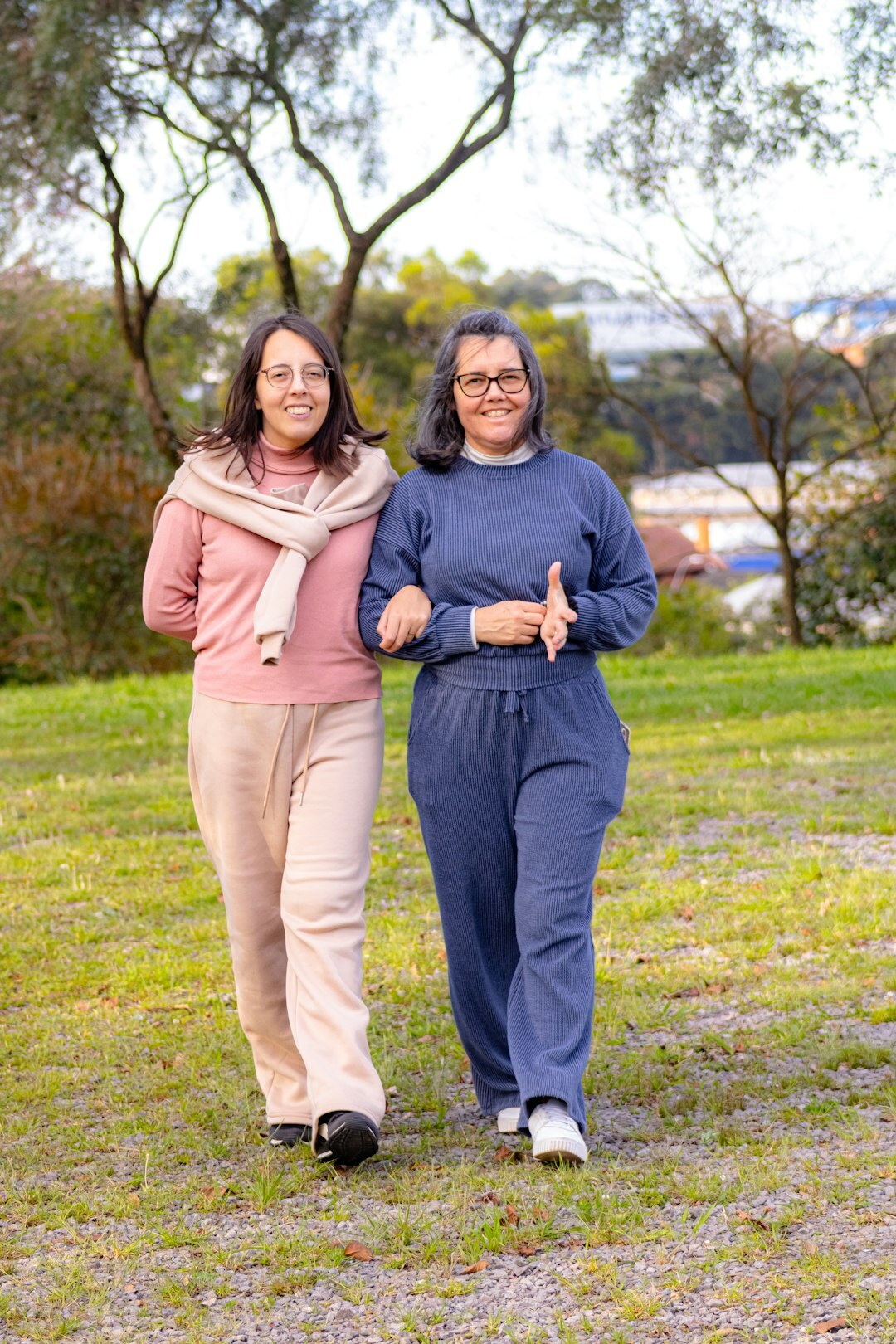 Adult daughter walking outdoors with her senior mother